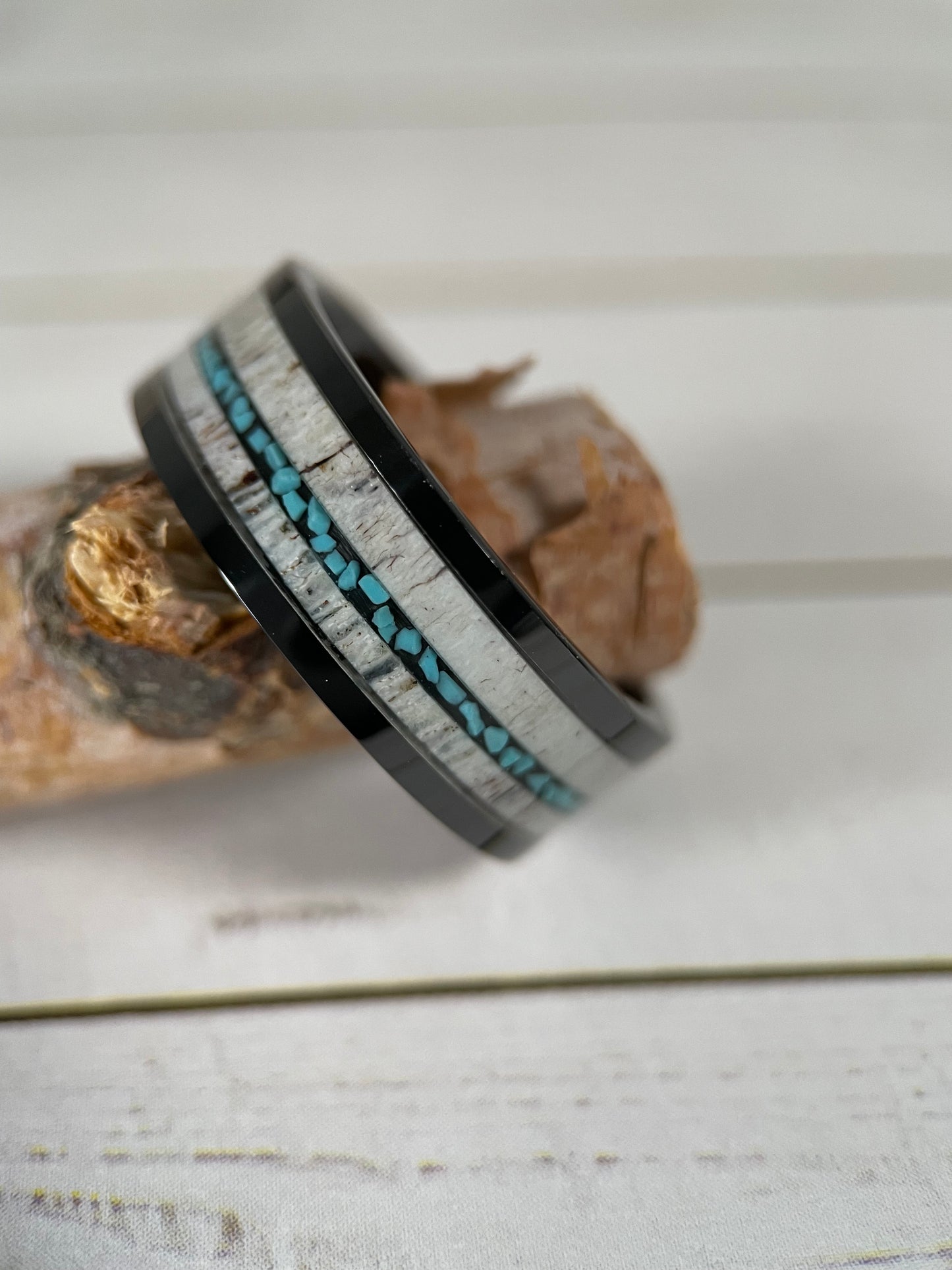 The Artemis black tungsten ring featuring a deer antler inlay with a turquoise vein.