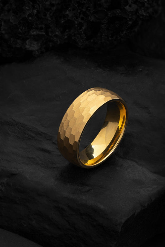 The Helios hammered tungsten ring featuring a rich 18k yellow gold PVD finish.