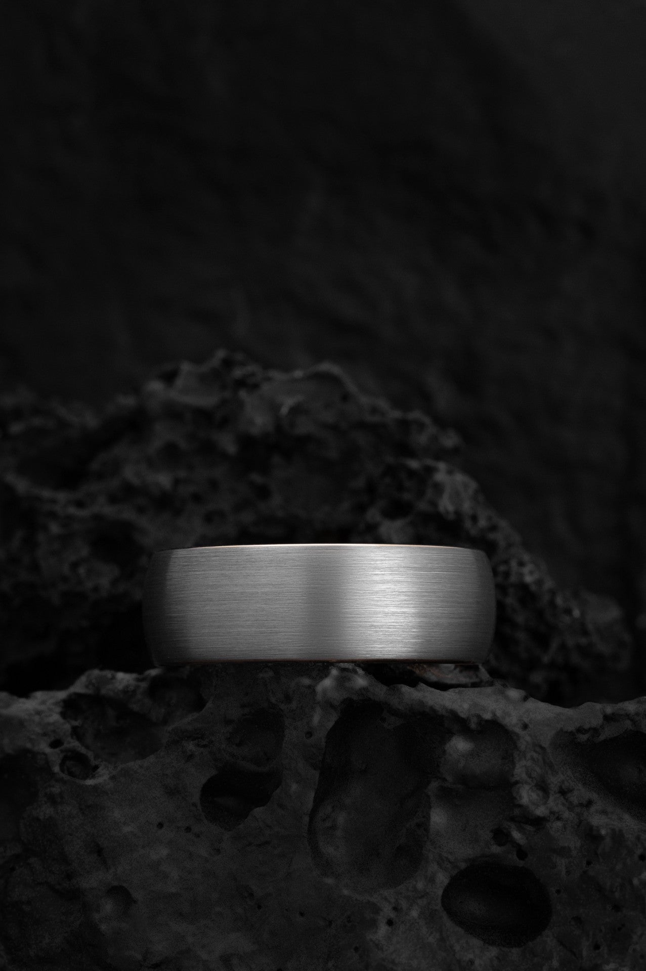 The Erebus gunmetal grey tungsten ring featuring a yellow gold interior and edges.