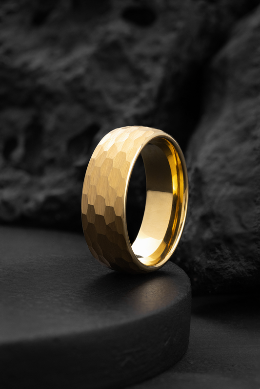 A hammered gold wedding band ring with a textured surface, displayed on a dark background.