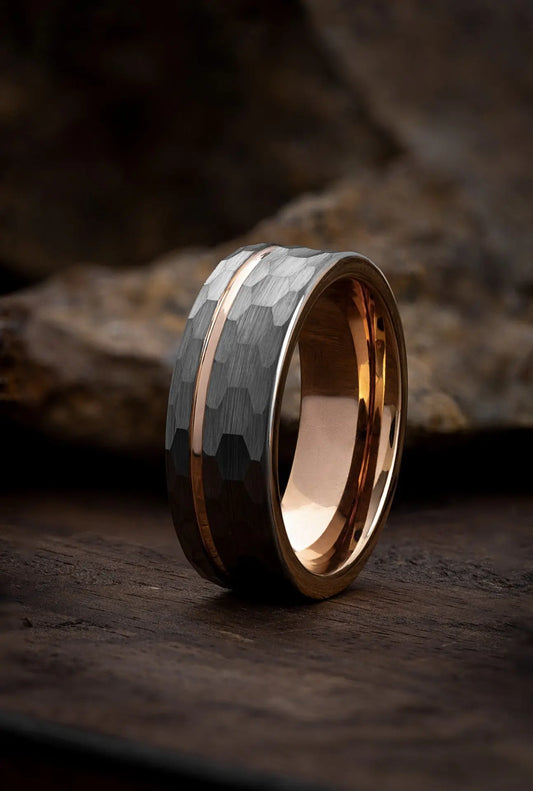 A polished tungsten carbide ring with a gold channel, displayed on a textured background.