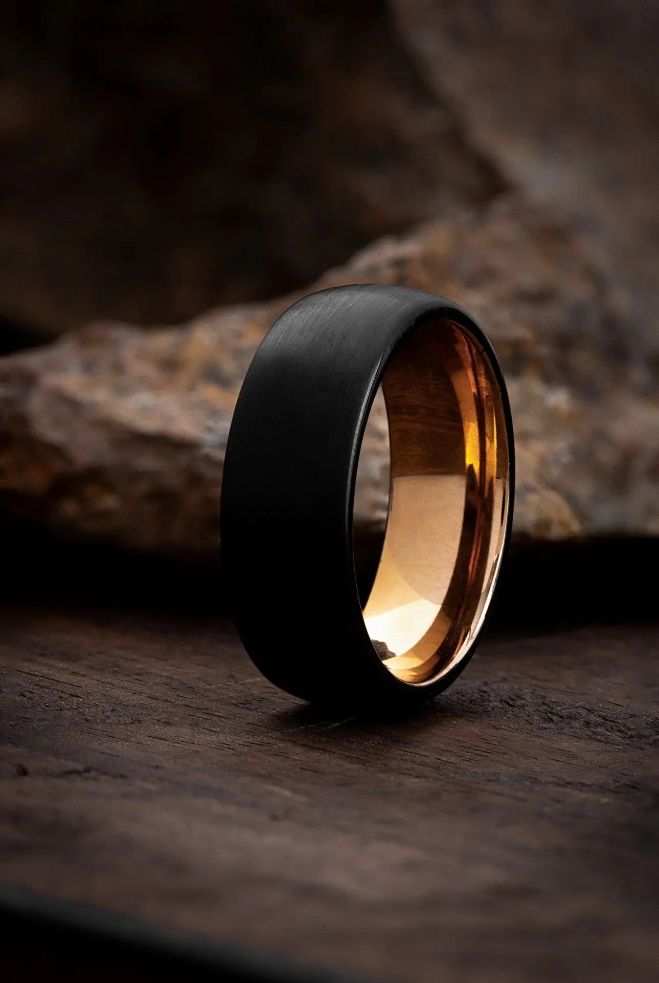 The Aquila rose gold tungsten ring featuring a brushed black exterior and polished interior.