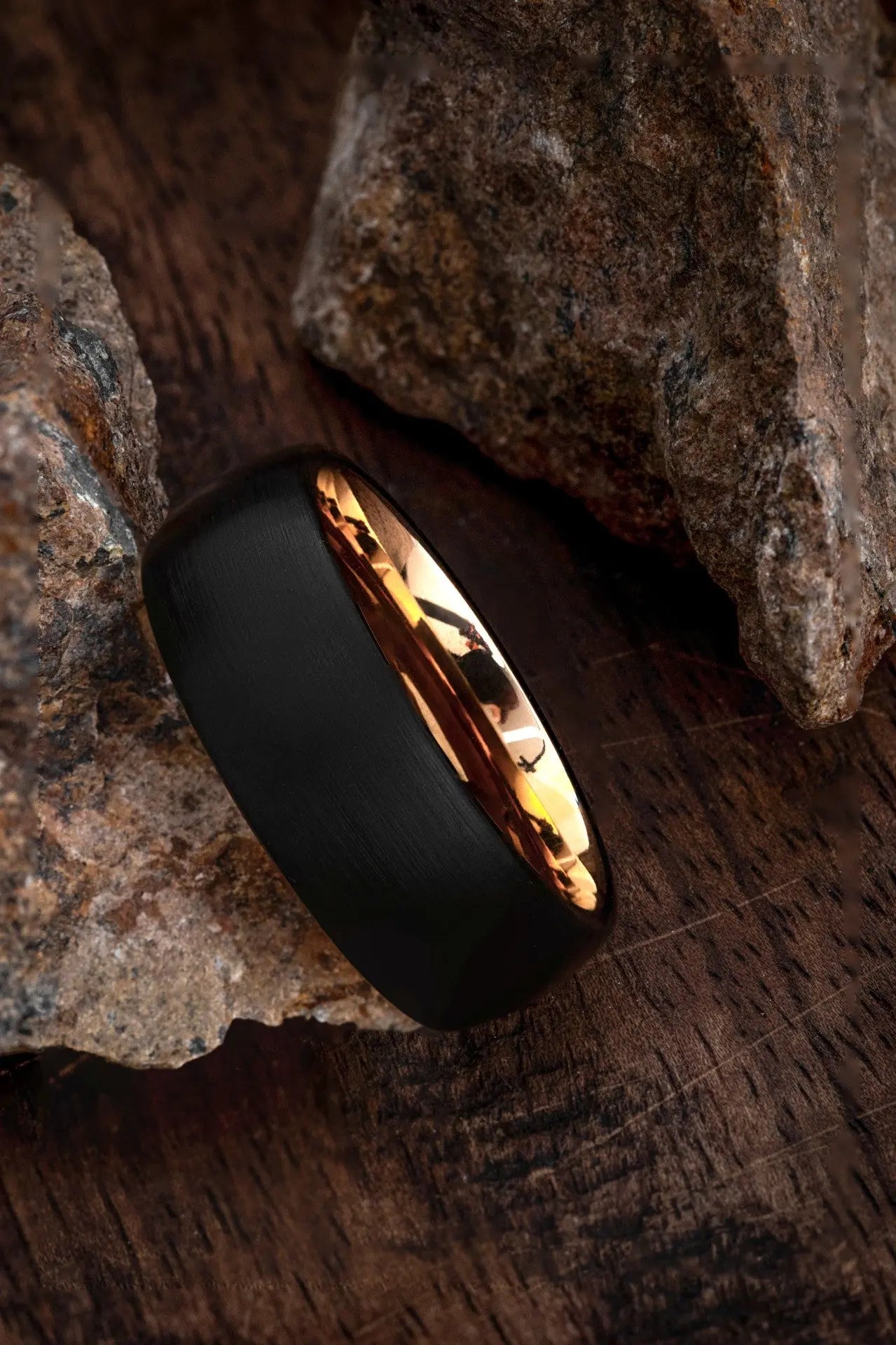 Close up of the two-tone contrast between the matte black tungsten and rose gold plating on a men's wedding band.