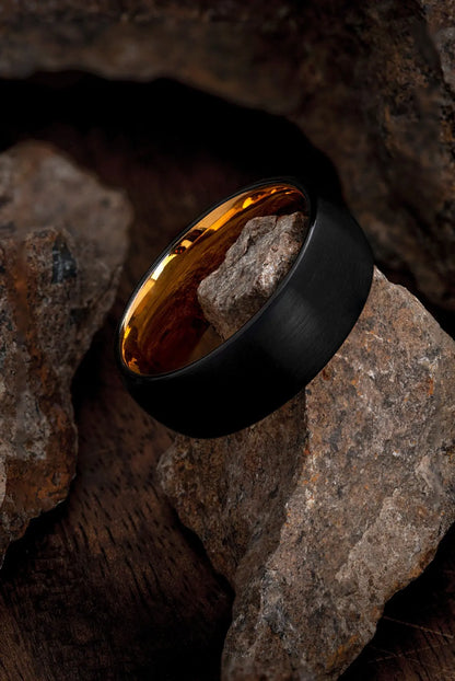 Man wearing The Aquila, a scratch-resistant black and rose gold wedding ring.
