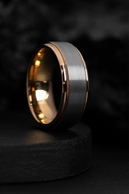 A rose gold and tungsten carbide classic ring with a brushed finish, displayed on a dark background.