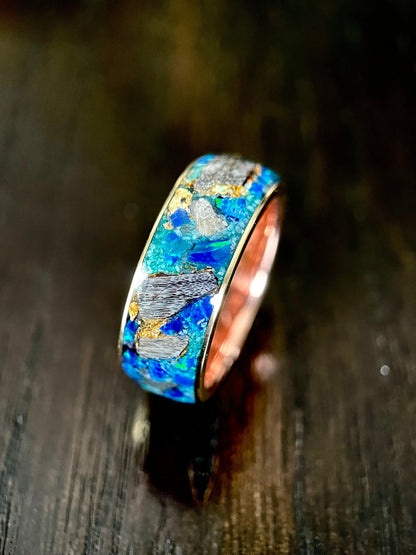 Regalia Rings Glaucus ring with multicolored opal, dinosaur bone, and meteorite fragment set in brass, displayed on dark surface.