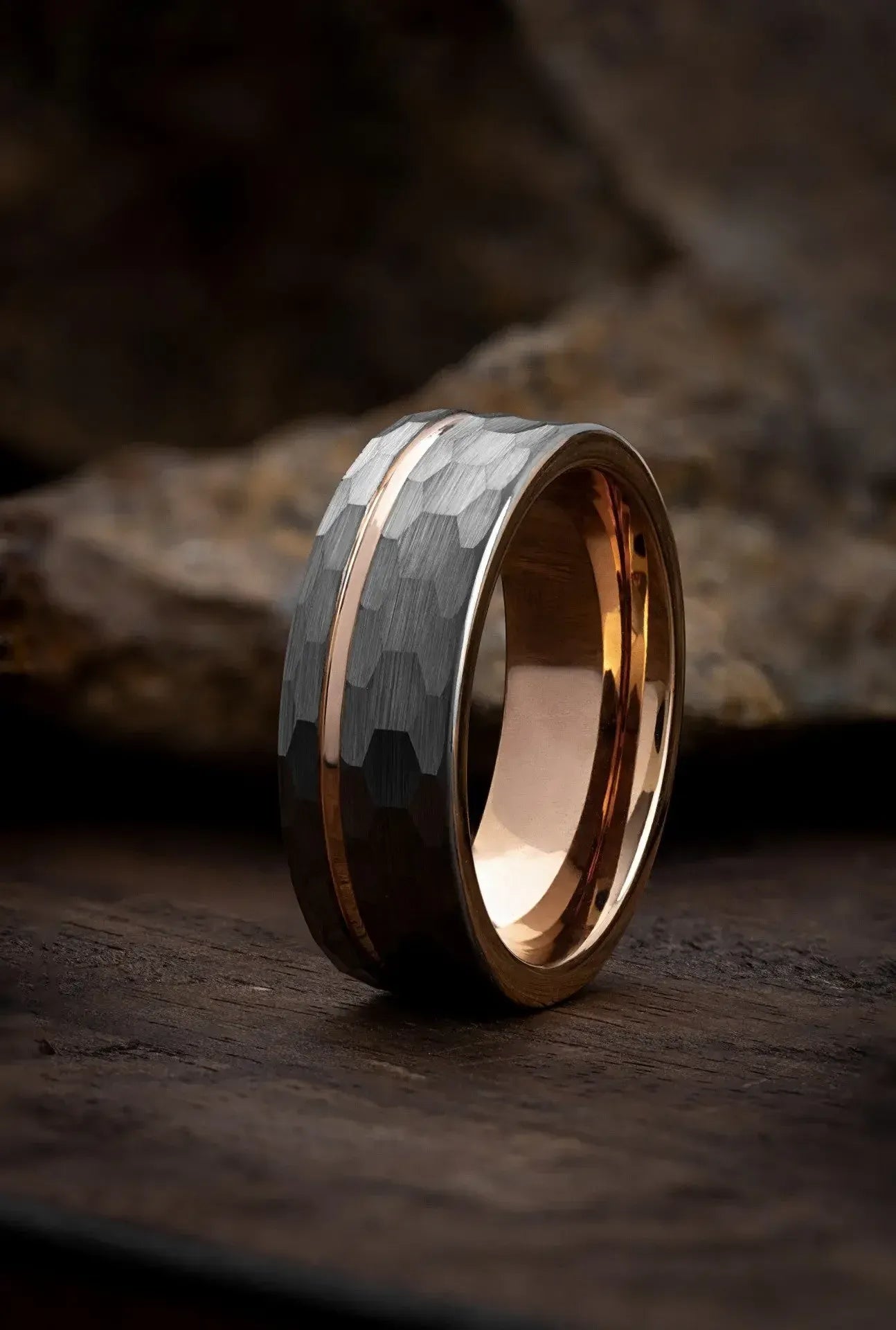 Polished tungsten carbide ring by Regalia Rings with hammered finish and gold channel design on textured background.