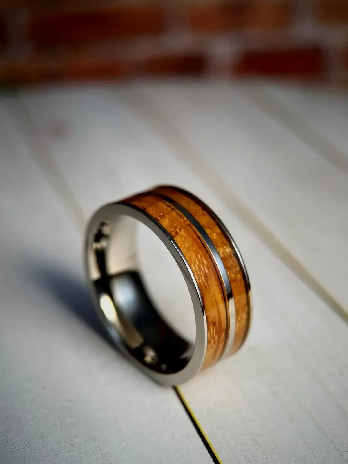 Close-up of a handcrafted wedding band made from reclaimed whiskey barrel oak with unique grain patterns and distillery marks.