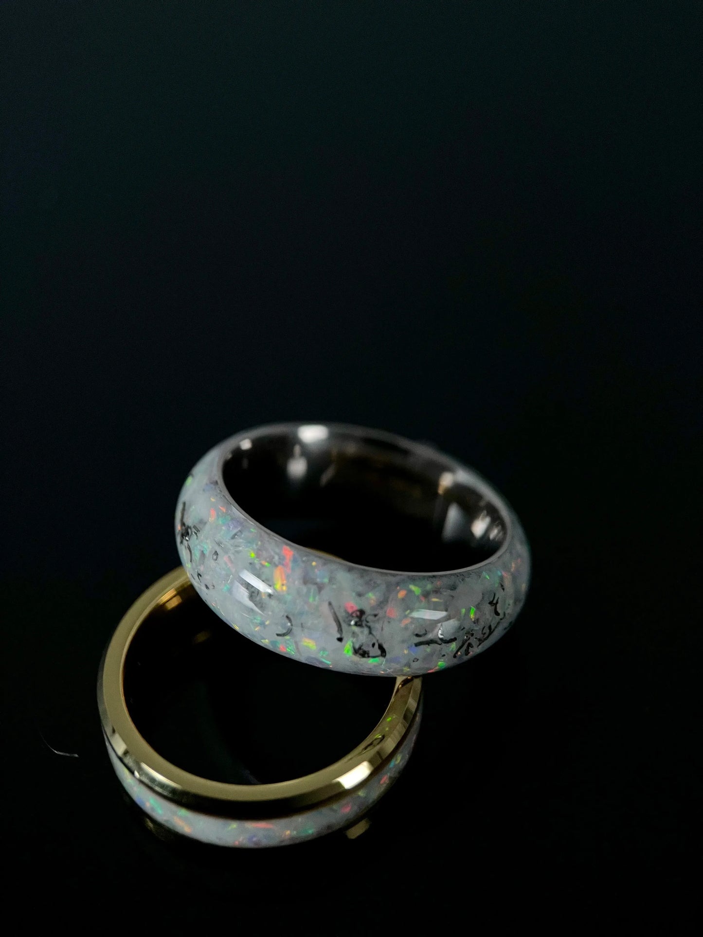 Close-up of Regalia Rings Phobos ring featuring crushed meteorite and blue opal fragments forming a galaxy pattern on a black band.