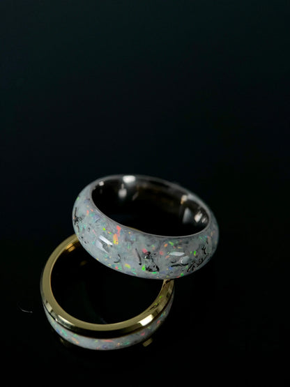 Close-up of Regalia Rings Phobos ring featuring crushed meteorite and blue opal fragments forming a galaxy pattern on a black band.