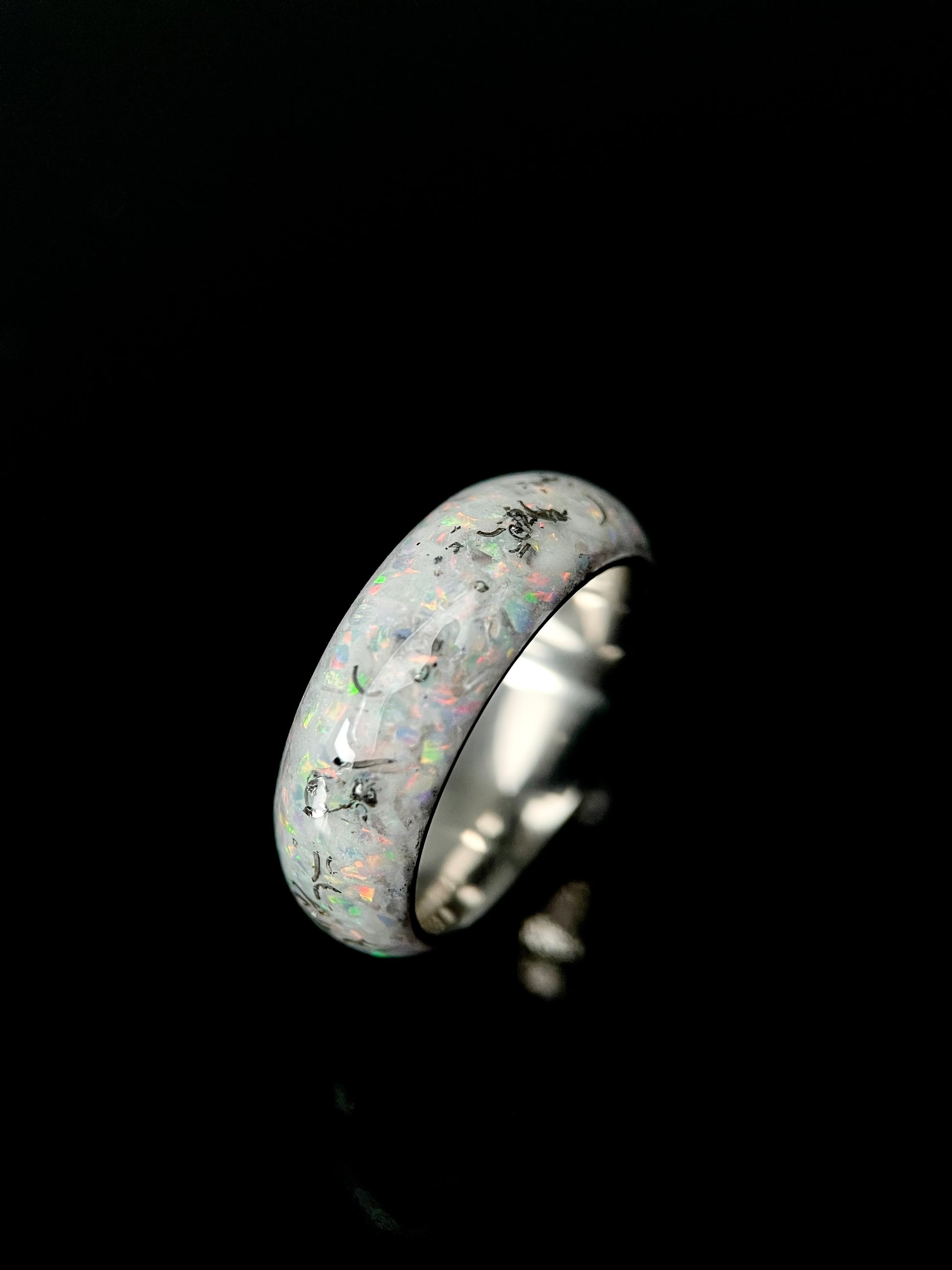 The Phobos ring glowing in the dark with luminescent blue opal inlay against a black background.