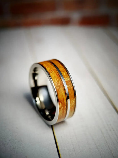 Regalia Rings whiskey barrel and titanium ring resting on reclaimed American white oak distillery staves.