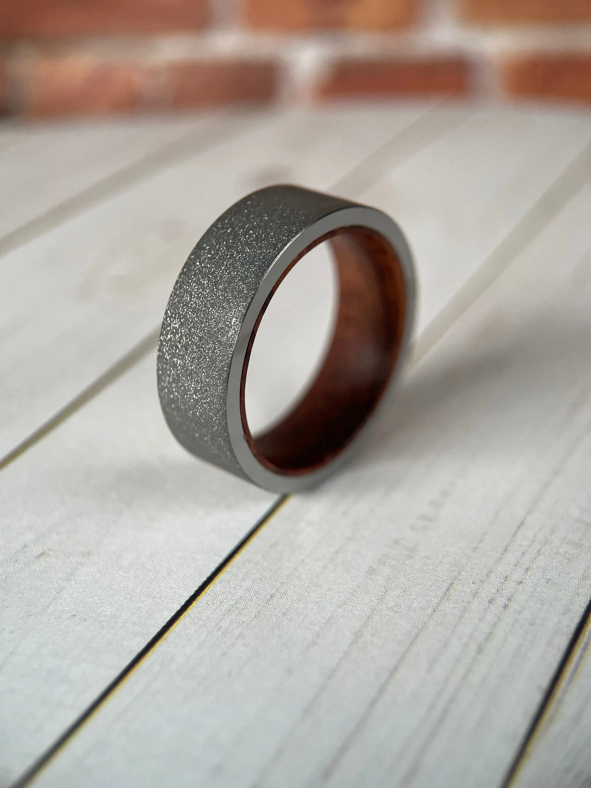 The Prometheus Redwood Liner and Sandblasted Tungsten Band by Regalia Rings, featuring a textured tungsten finish and natural wood inlay.