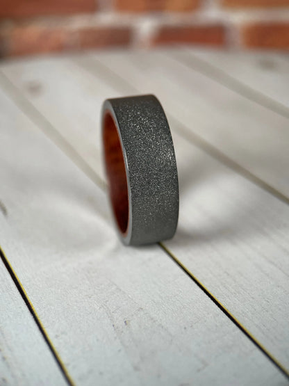 Regalia Rings Prometheus Redwood Liner and Sandblasted Tungsten Band, showcasing the textured wood-inspired interior and matte finish.
