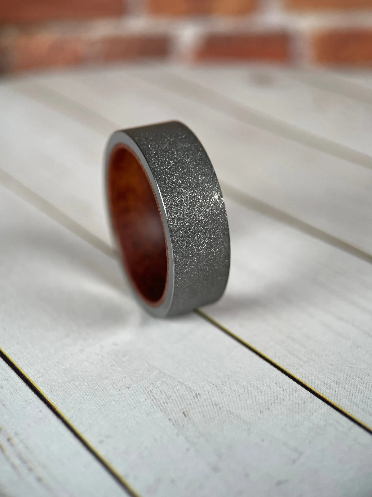 Regalia Rings The Prometheus Redwood Liner and Sandblasted Tungsten Band, showcasing a textured tungsten ring with a redwood liner detail