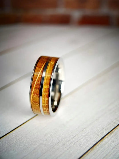 Polished Grade 5 titanium wedding band with comfort-fit interior, set inside a whiskey barrel, highlighting the precision-machined dome profile.