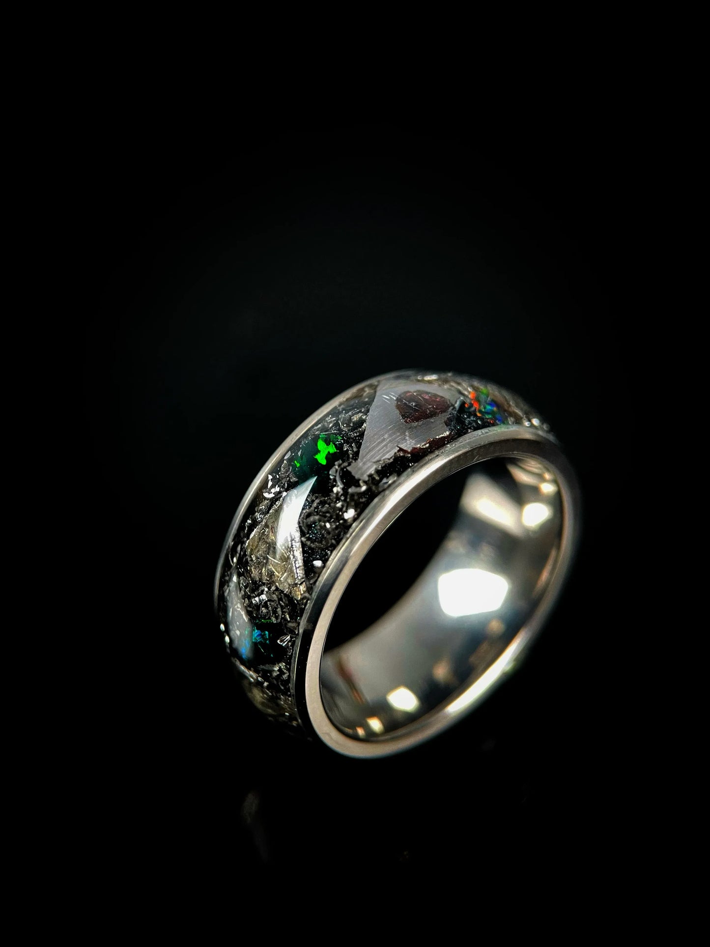Titanium wedding band by Regalia Rings featuring meteorite inlay and fire opal accents on a sleek, polished ring design.